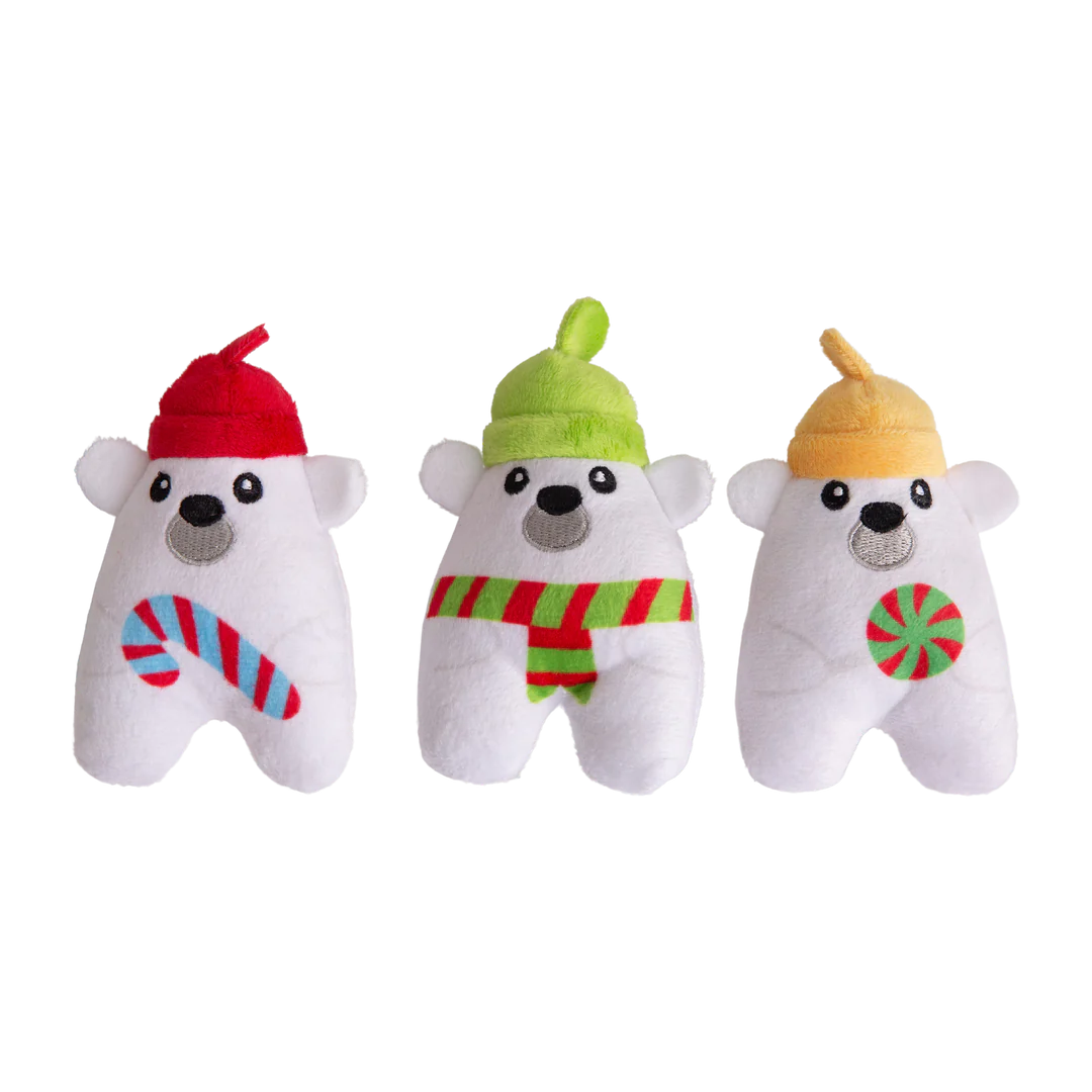 The Snugarooz Hide & Seek Igloo features three plush polar bears in festive hats and scarves, standing before a pastel blue igloo with Christmas lights. Hide treats inside for interactive, holiday fun with your pup!.