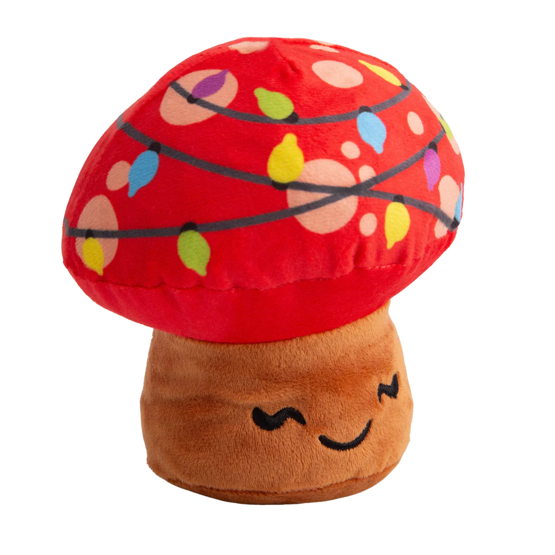 The Snugarooz Merry Mushroom is a plush dog toy shaped like a smiling mushroom with a red cap, colorful string lights, and brown stem—perfect for festive holiday fun.
