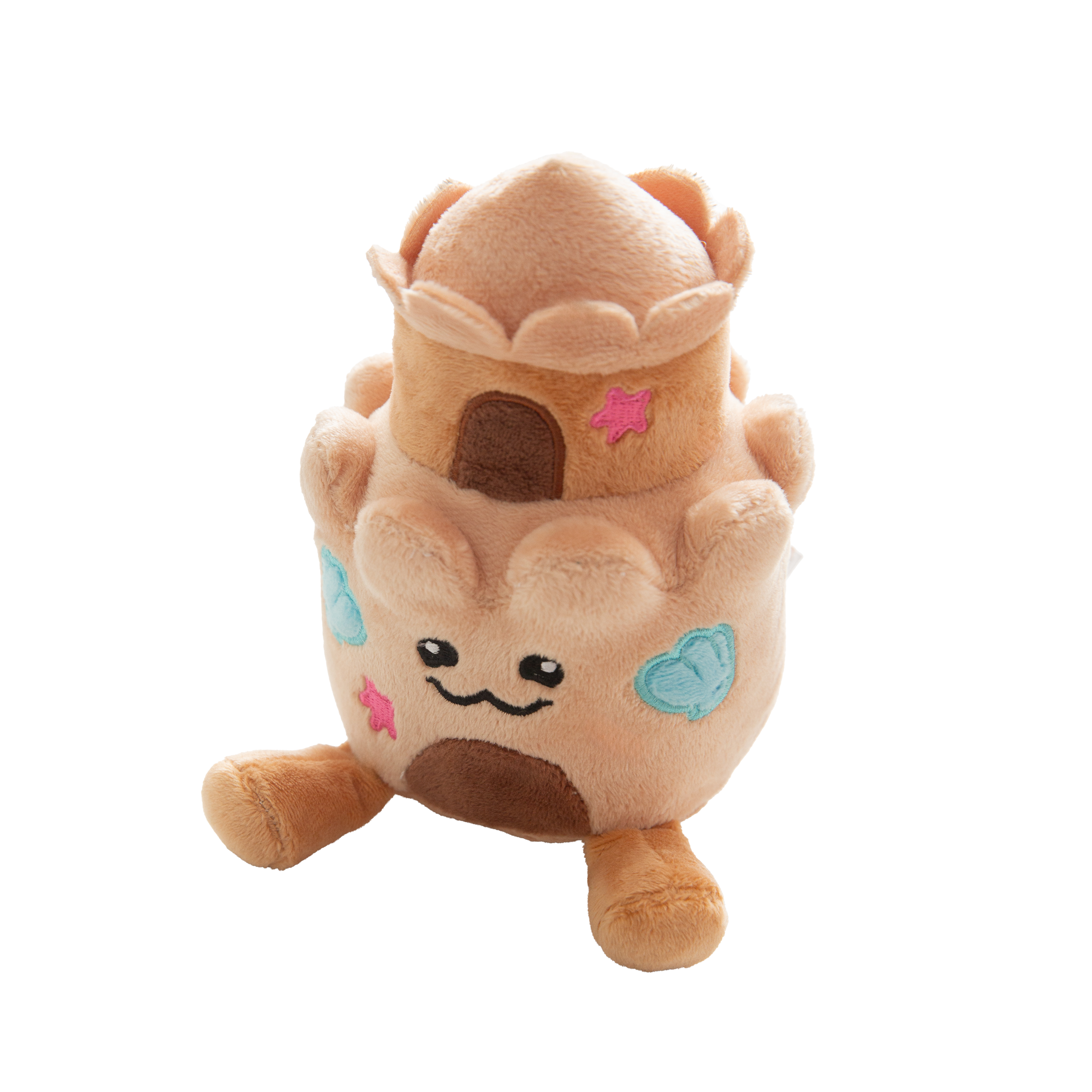 The Snugarooz Snugz Castle is a plush dog toy shaped like a sandcastle, featuring a smiling face, blue shell designs, pink starfish accents, and a brown doorway on a white background.